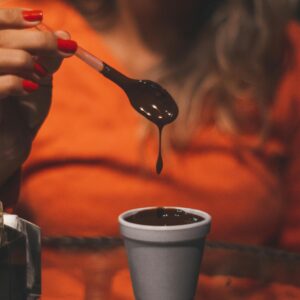 Woman holding a spoon of melted chocolate over a cup indoors, Monte Verde.