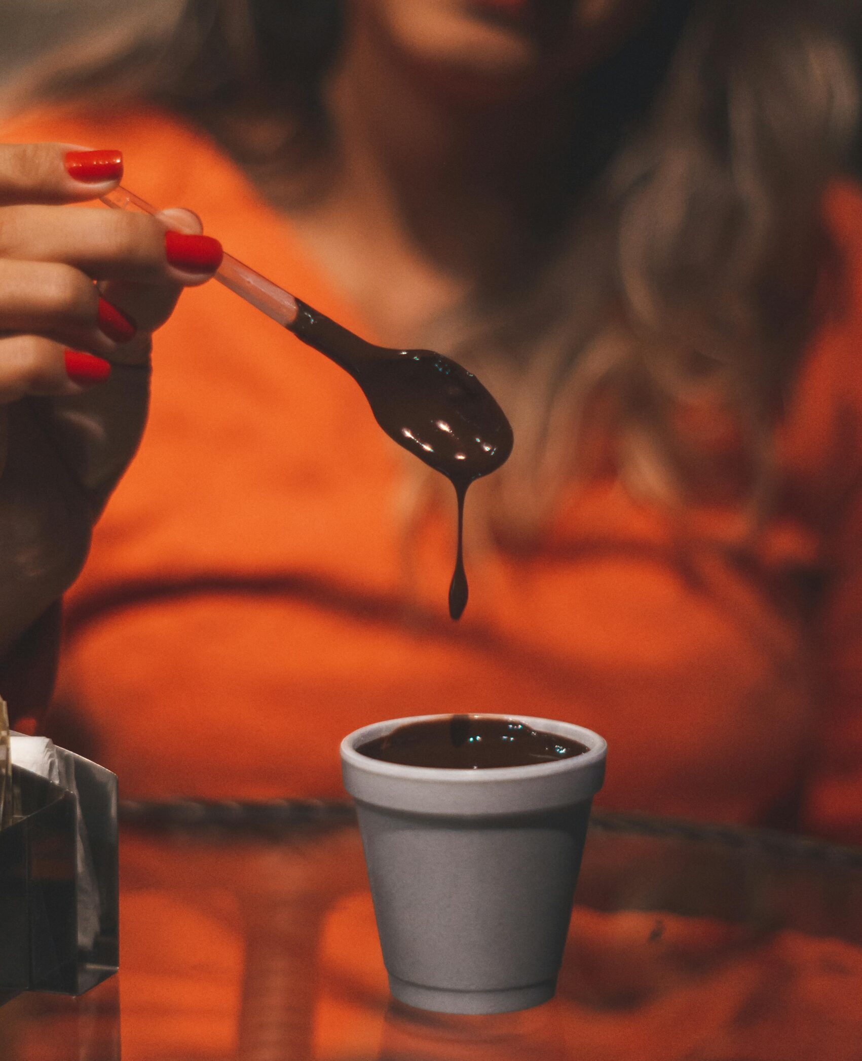 Woman holding a spoon of melted chocolate over a cup indoors, Monte Verde.