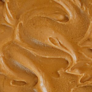 Smooth and creamy peanut butter texture with swirls, perfect for food and culinary themes.