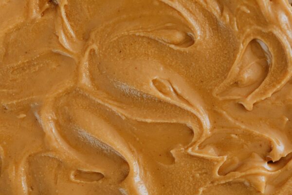 Smooth and creamy peanut butter texture with swirls, perfect for food and culinary themes.